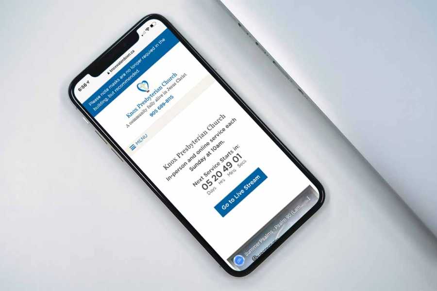 iPhone on a desk showing home page of the Knox Waterdown web site.